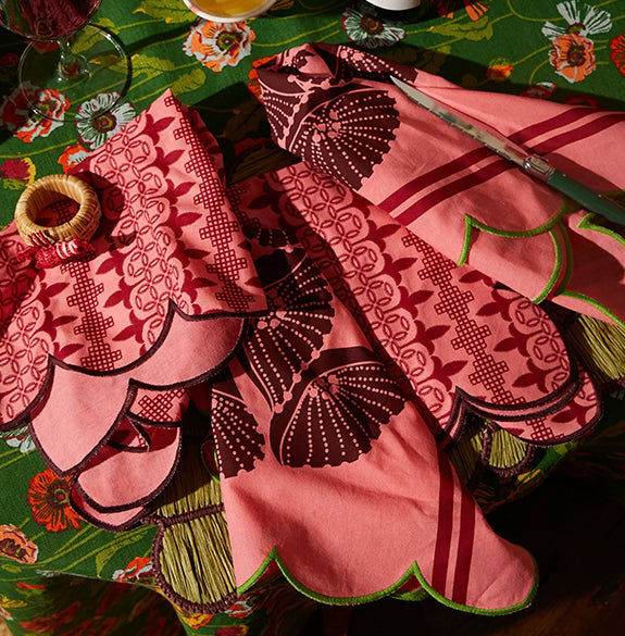 Decorative pink and red embroidered table runner on a patterned tablecloth.