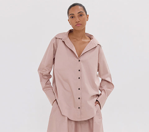 Woman wearing a light pink outfit with a matching jacket and pants on a white background