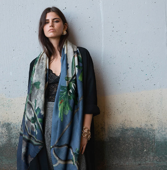 Woman wearing a floral-patterned scarf against a textured wall.