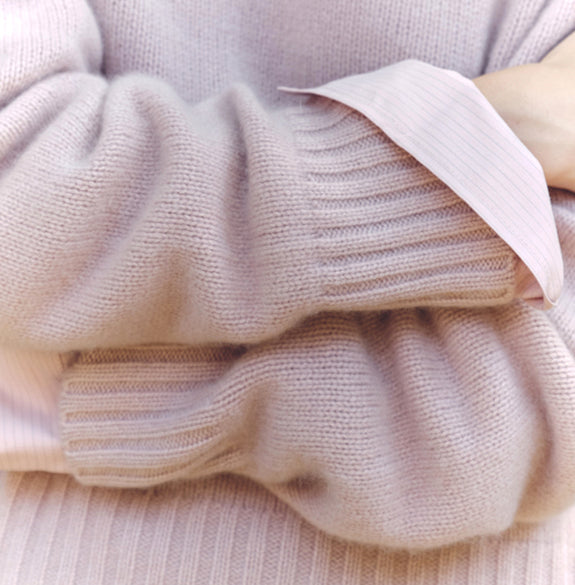 Close-up of a light pink sweater with a focus on texture and color.