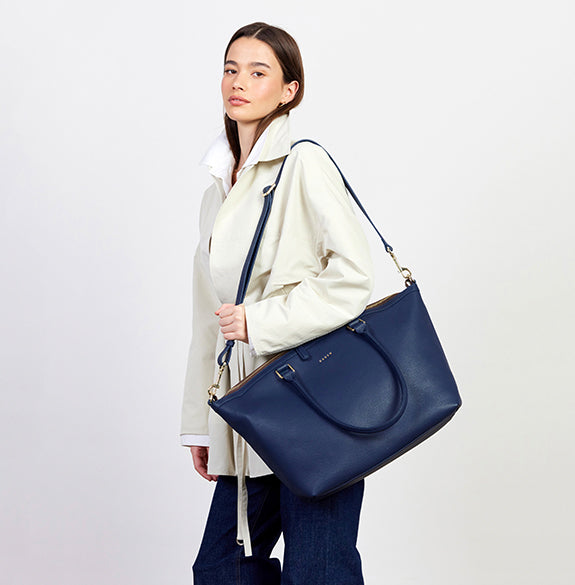 Woman holding a navy blue handbag against a white background