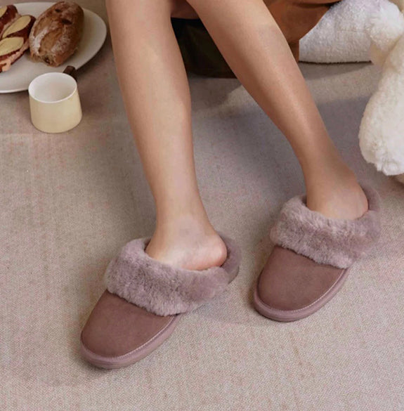Brown slippers with fuzzy trim worn indoors on a carpeted floor.