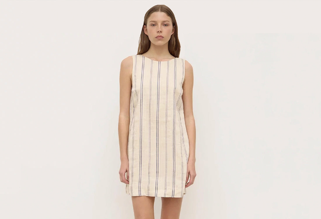 Woman wearing a sleeveless striped dress on a plain background
