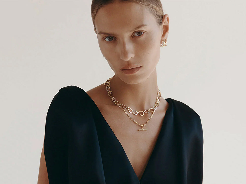 Woman wearing a couple of Kirstin Ash Gold necklaces.