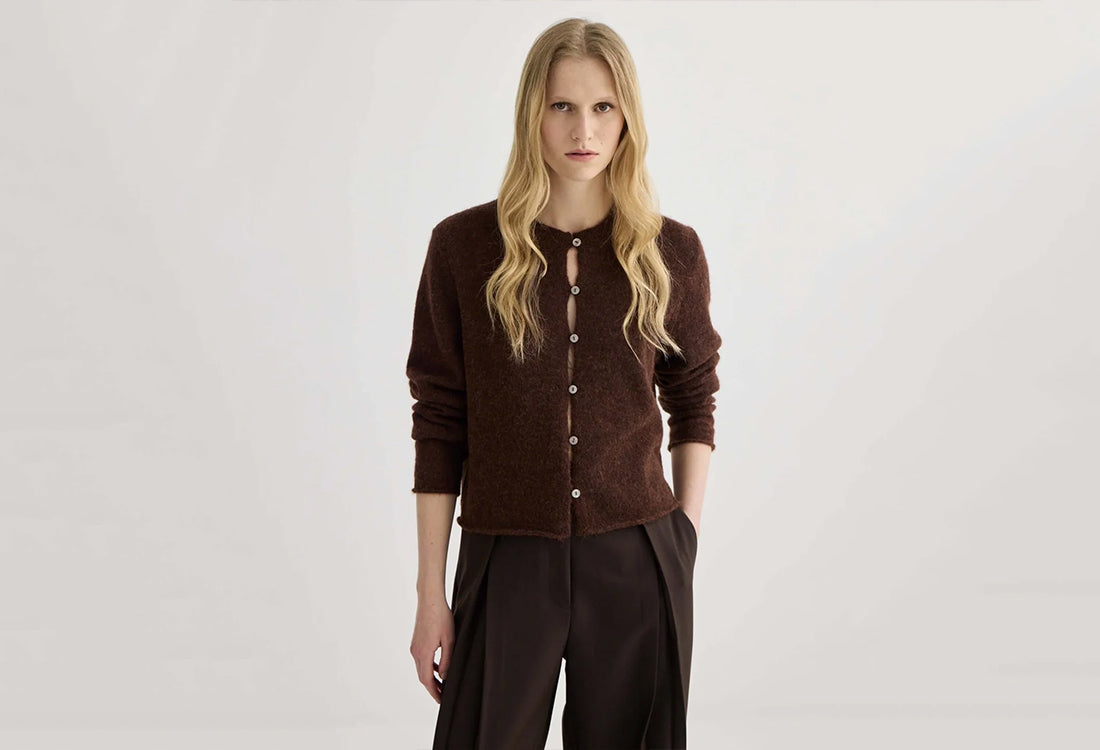 Woman wearing a brown cardigan and pants on a white background