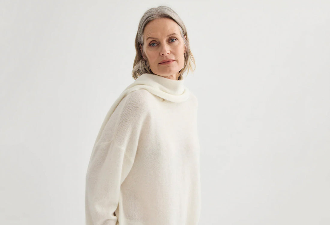 Woman wearing a white scarf against a plain background