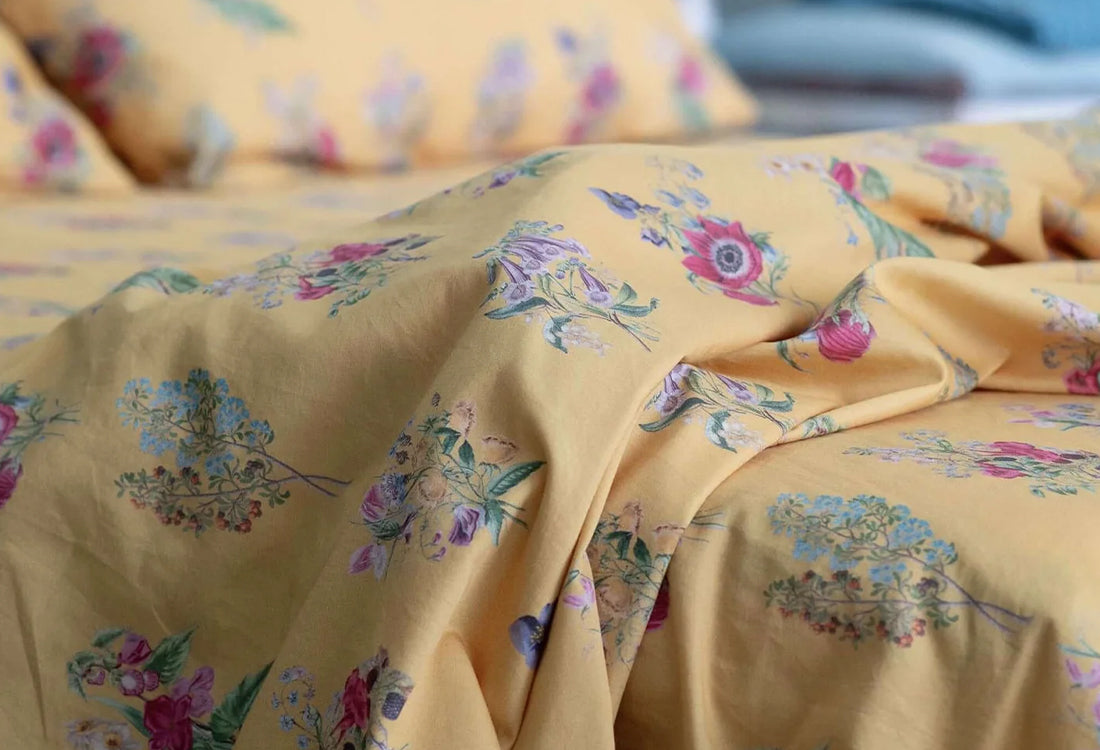 Floral patterned fabric on a bed with pillows in the background