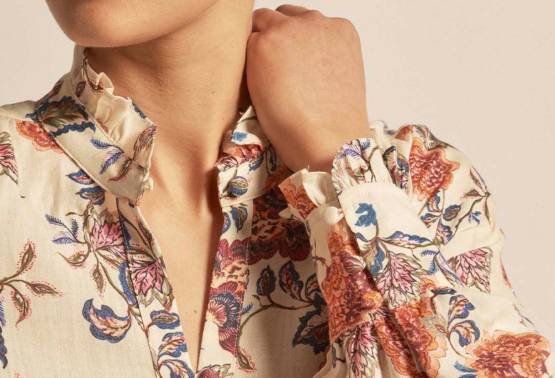 Close-up of a person wearing a floral blouse with a beige background