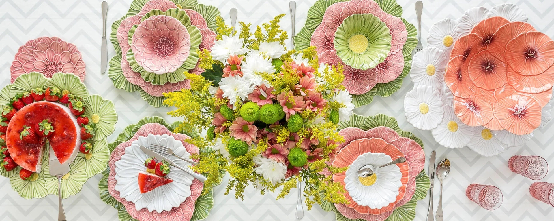 Colorful table setting with floral plates and silverware on a white tablecloth.