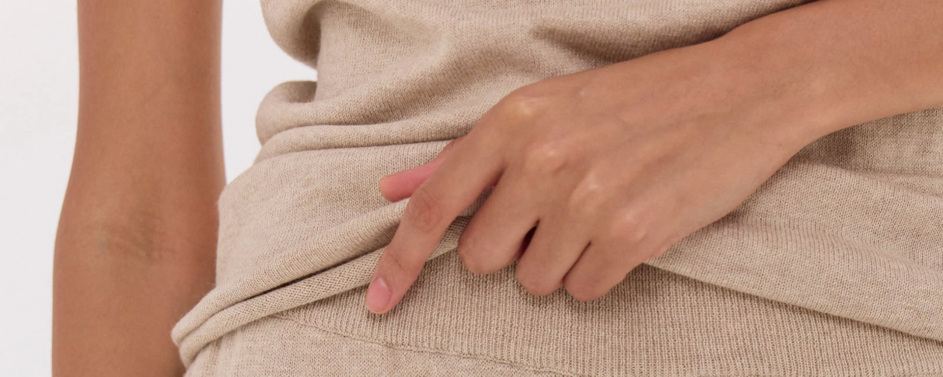Person wearing a beige towel or garment with a hand adjusting it.