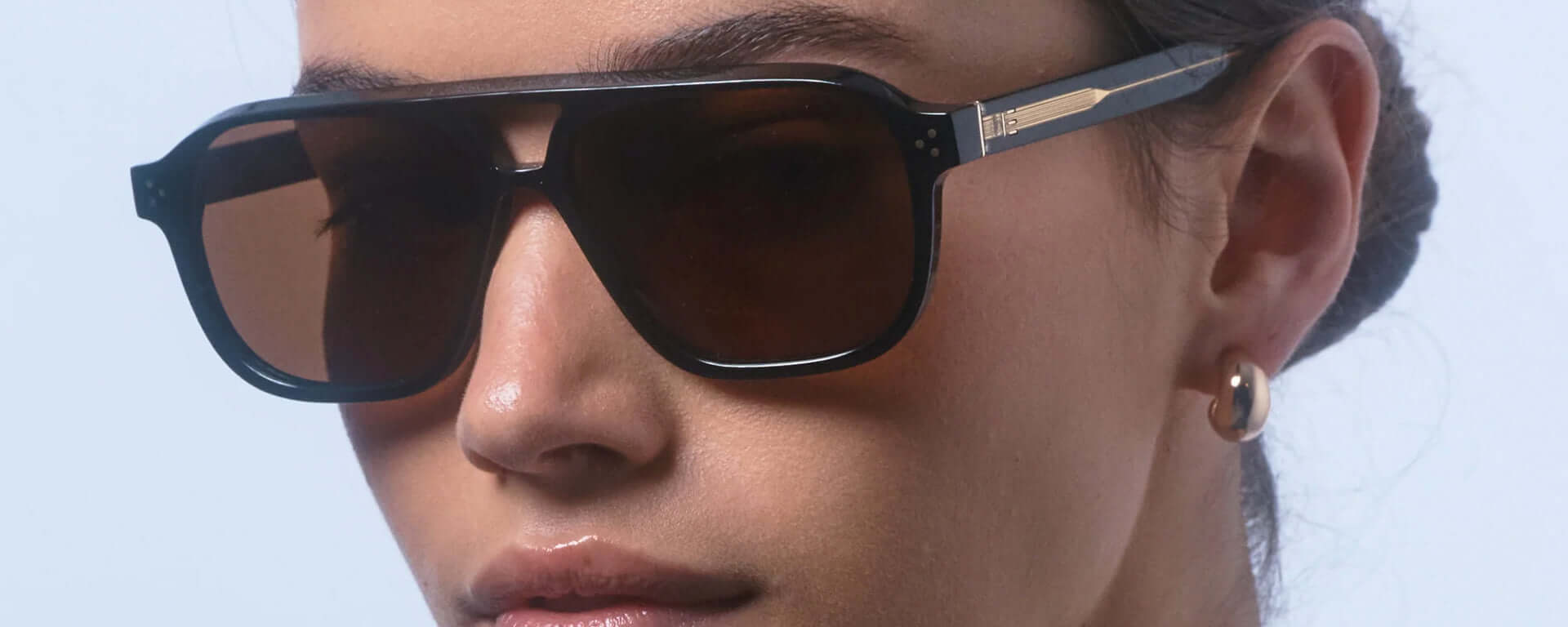 Close-up of a person wearing dark sunglasses with a blurred background