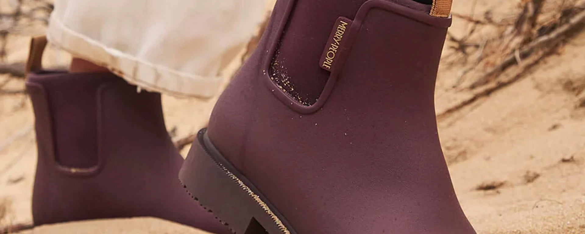 Purple boots with a brand logo on a sandy background