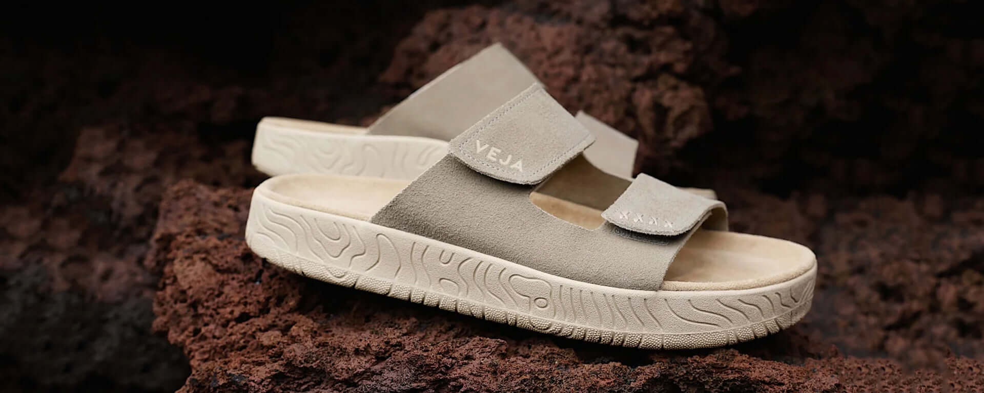 Pair of gray sandals with a strap on a textured brown surface