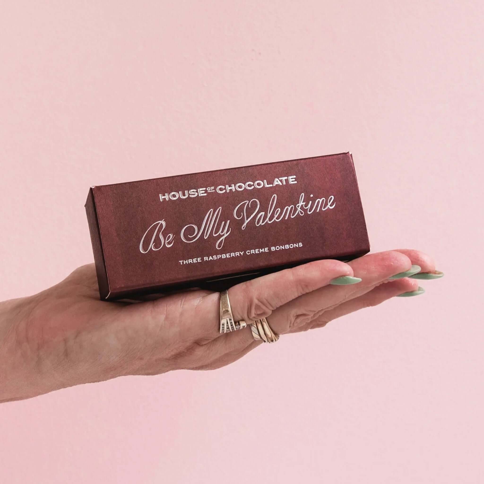 Alt Tag: House of Chocolate Be My Valentine Raspberry Creme Chocolate Bonbons box in hand, 3 bonbons in dark chocolate Valentine’s gift