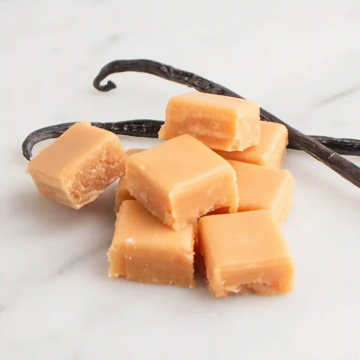 Vanilla bean fudge and vanilla on a marble surface.