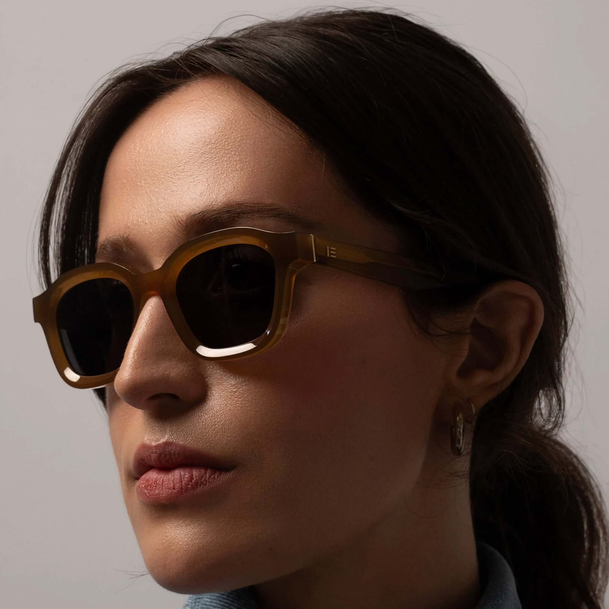 Alt Tag: Isle of Eden Sunglasses - Harley Dijon worn by model, unisex bold bio-acetate frame with flat lenses and gold temple trims