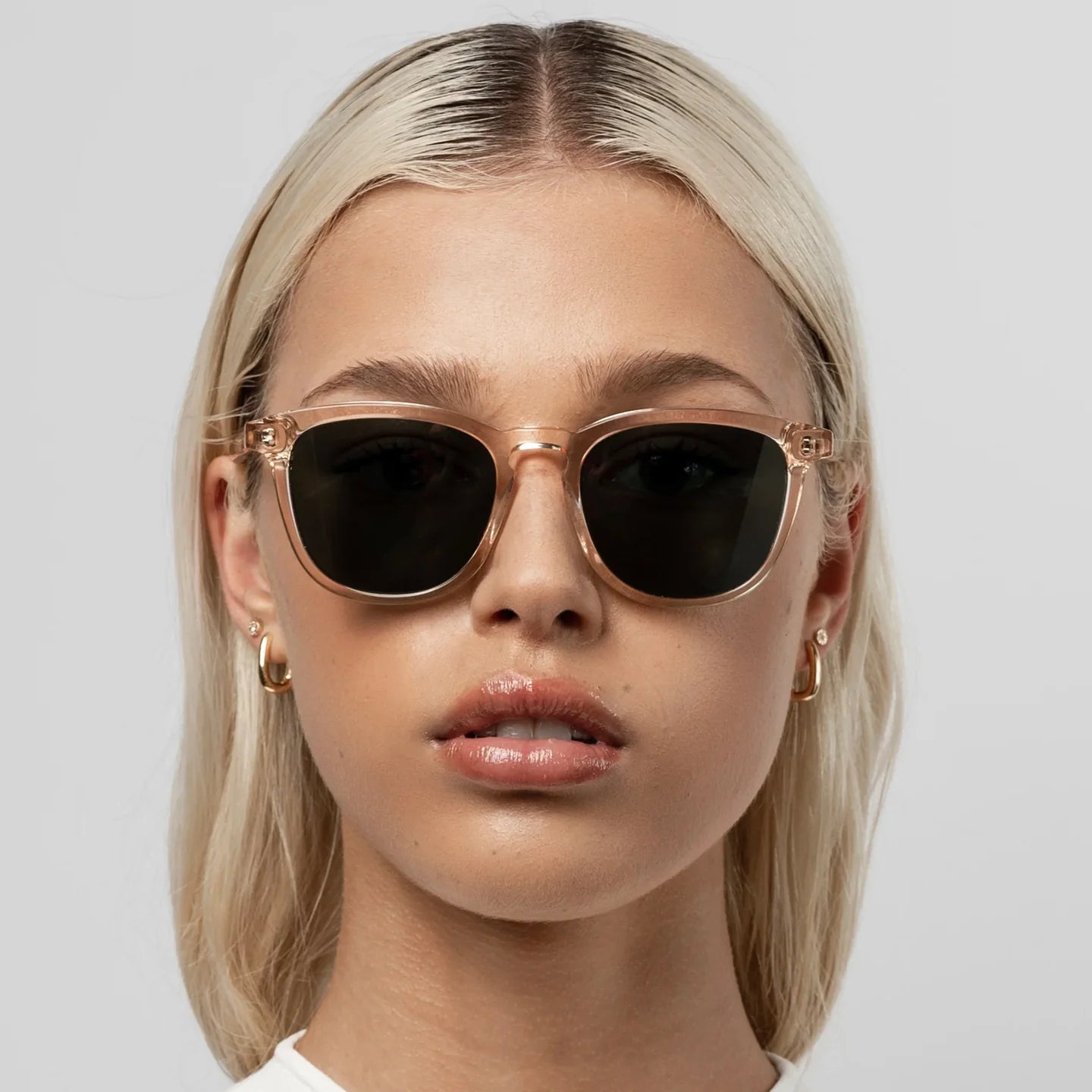 Woman wearing gold-framed sunglasses with a plain background