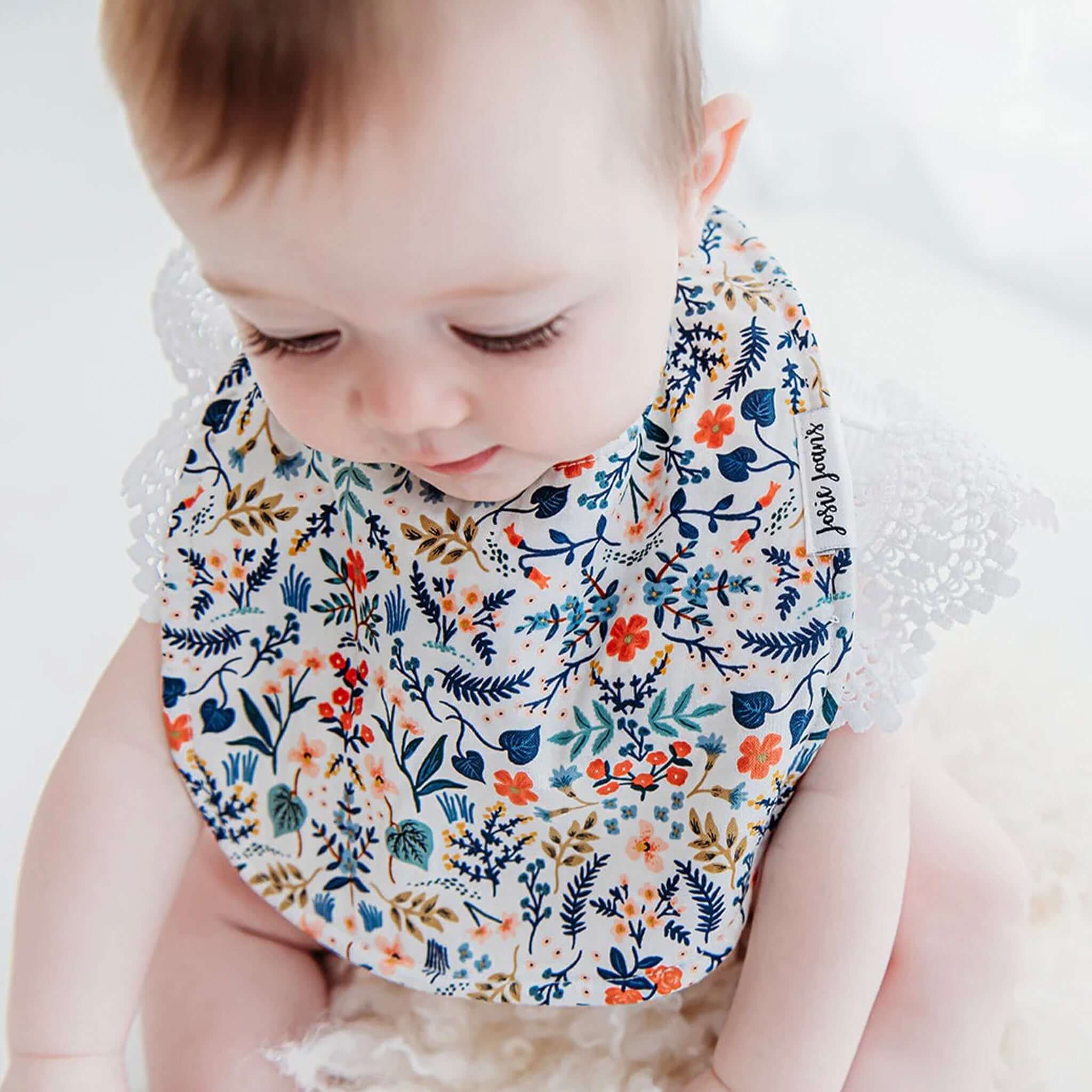 Alt Tag: Josie Joan's Linen Bib - Goldie floral linen baby bib with micro fleece backing and snap buttons, worn by baby