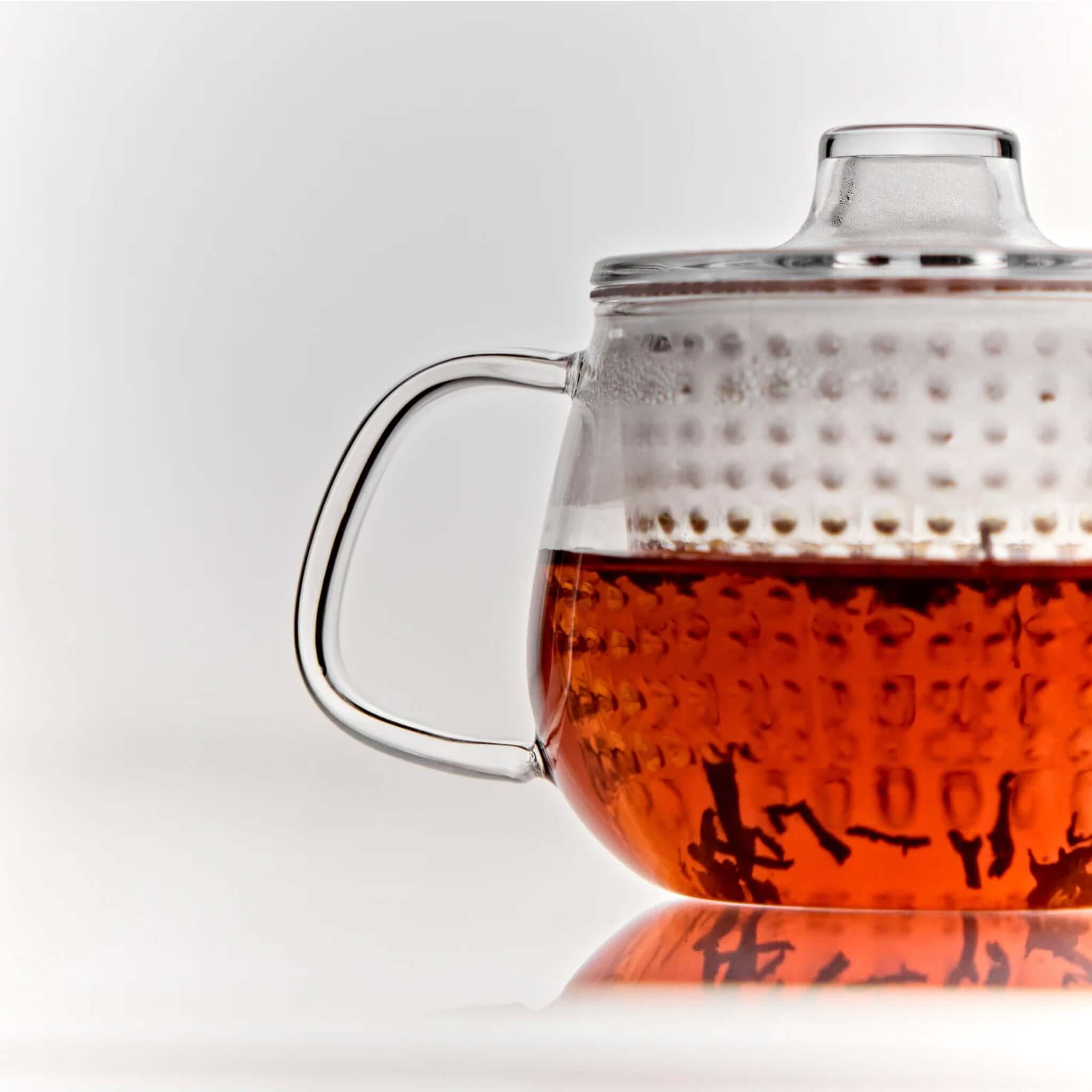 Alt Tag: Kinto Unitea Unimug heat-resistant glass tea mug with strainer and lid, loose-leaf tea infusing in amber brew