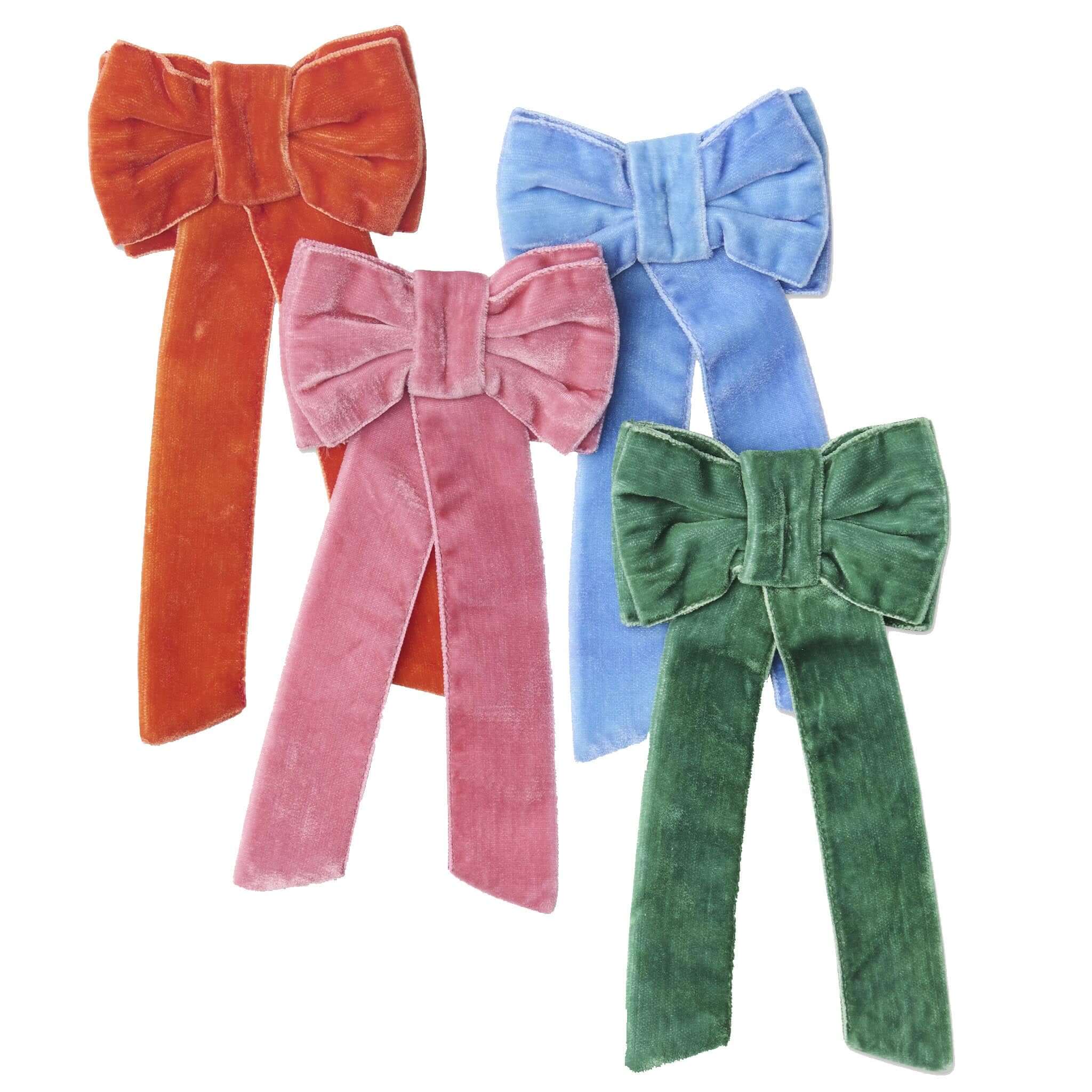 Four colorful velvet bows in orange, pink, blue, and green on a white background.