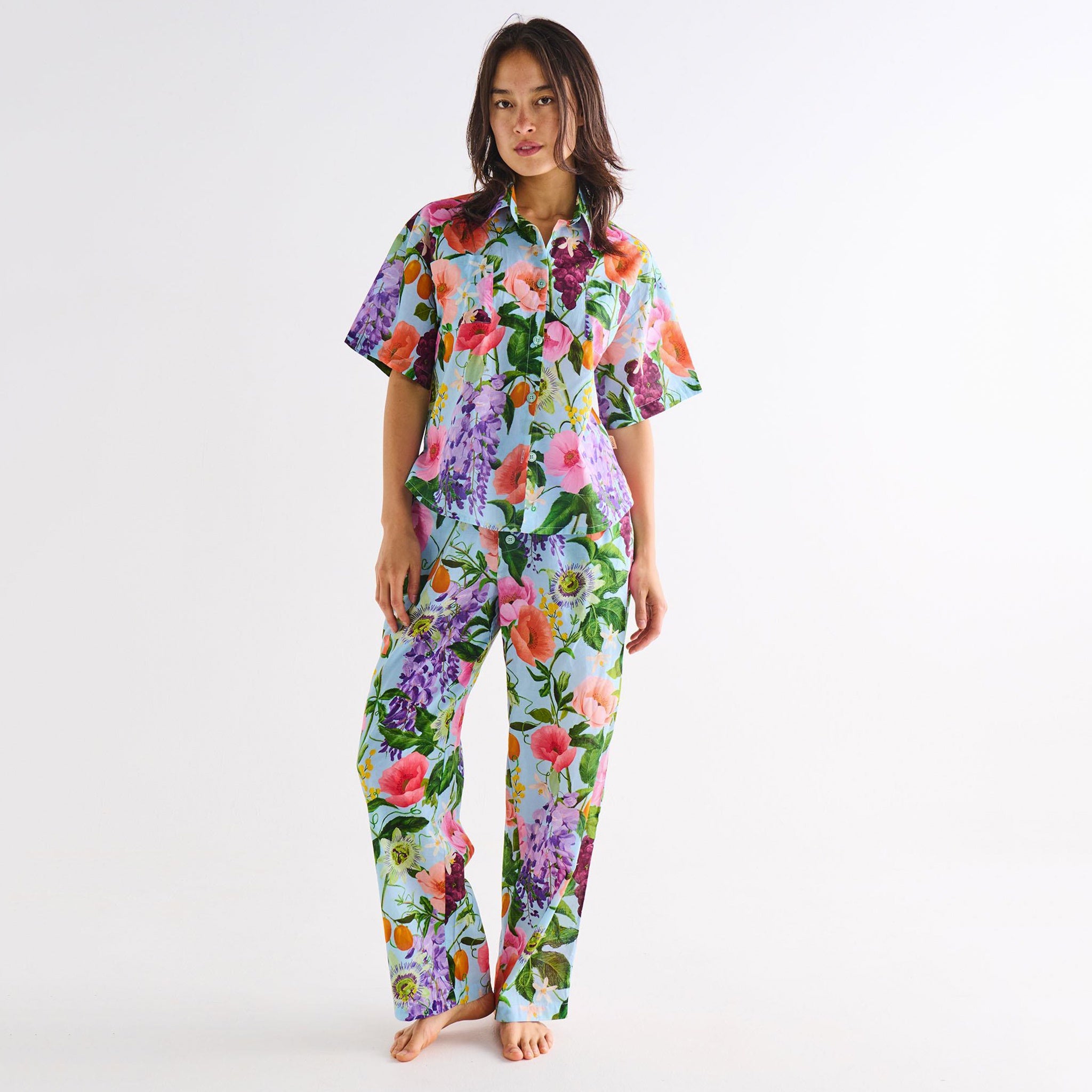 Woman wearing a colorful floral pajama set on a white background