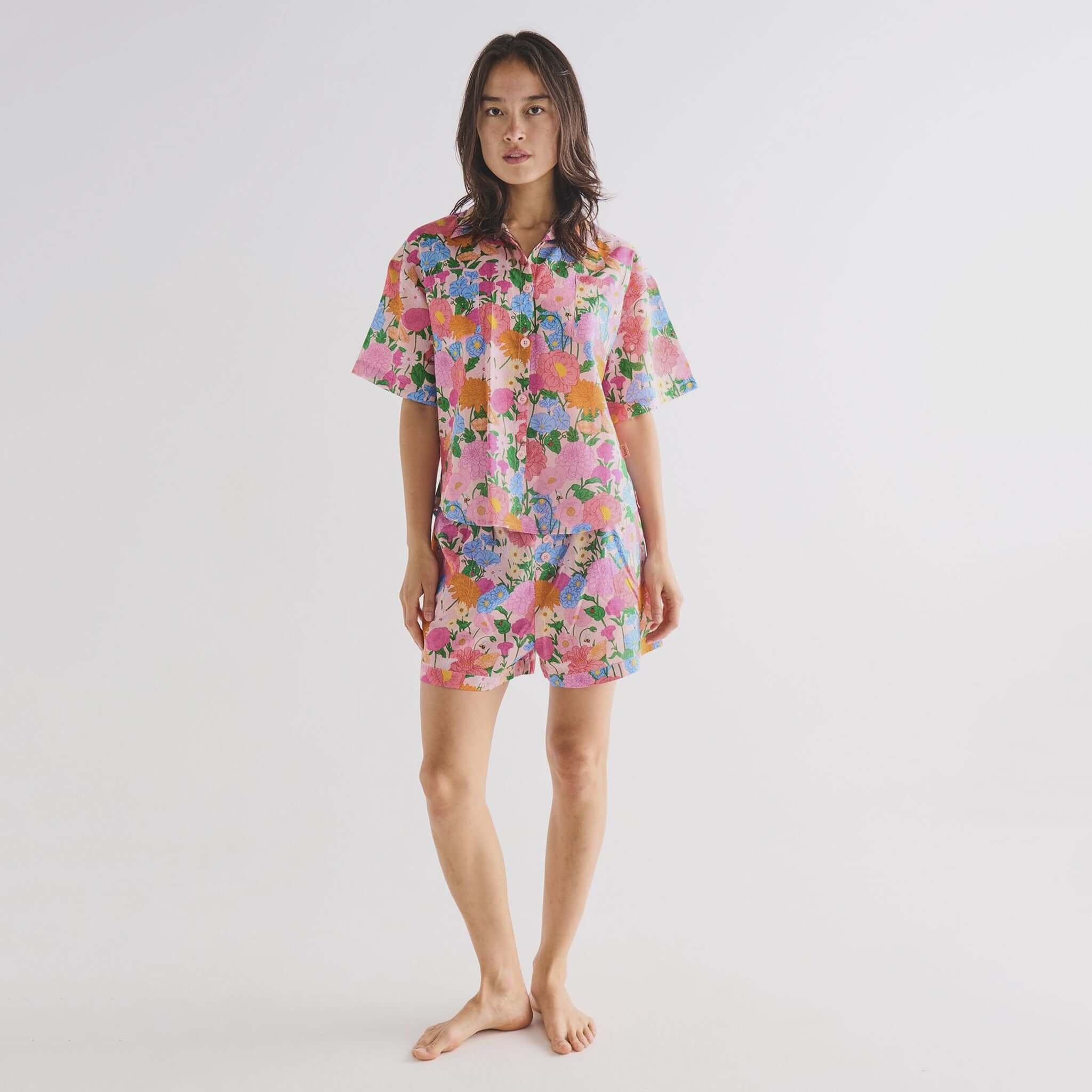 Alt Tag: Kip & Co Organic Cotton Short Sleeve Shirt & Shorts Pyjama Set - Follow the Sun floral pink button-up shirt and shorts on model