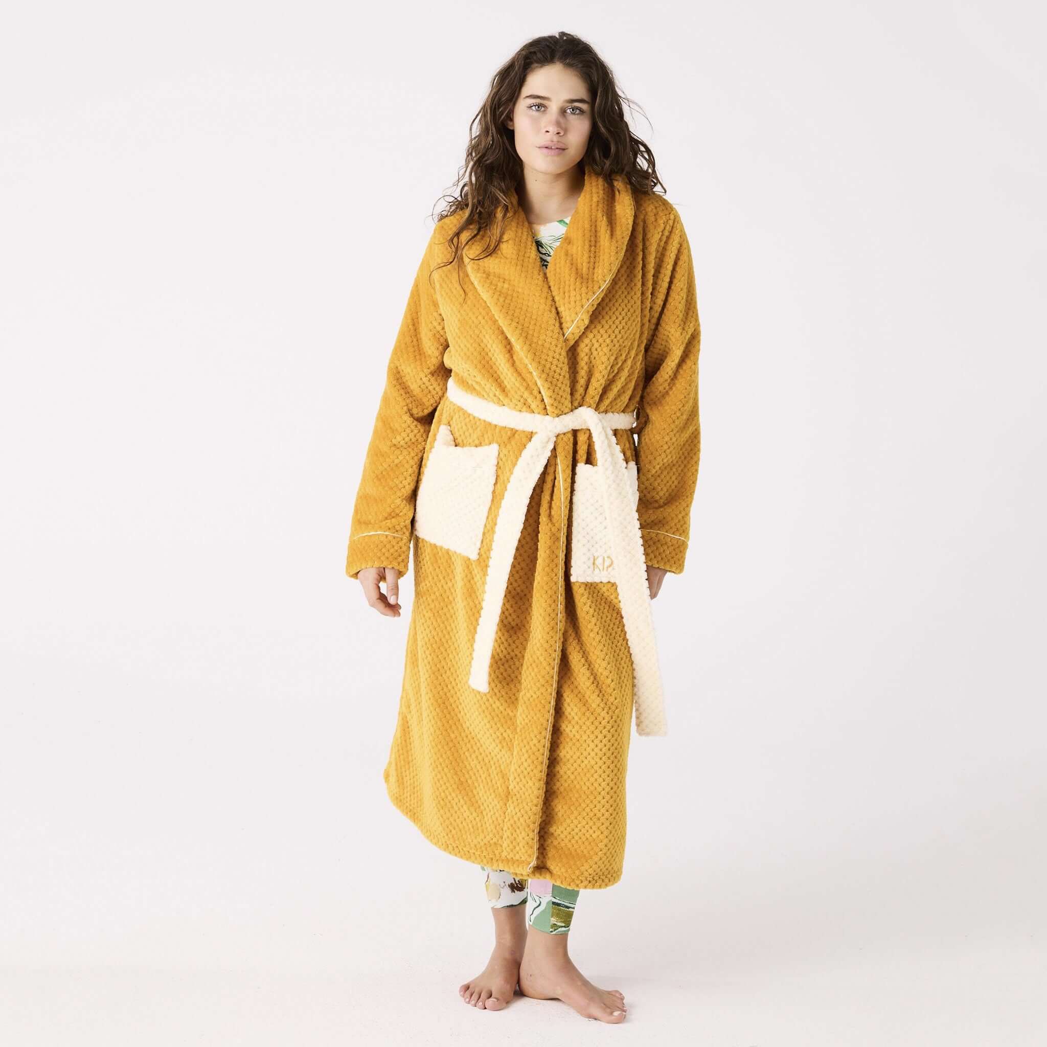 Alt Tag: Kip & Co Cosy Robe - Desert Sand quilted mustard robe with cream patch pockets and waist tie, model wearing full length