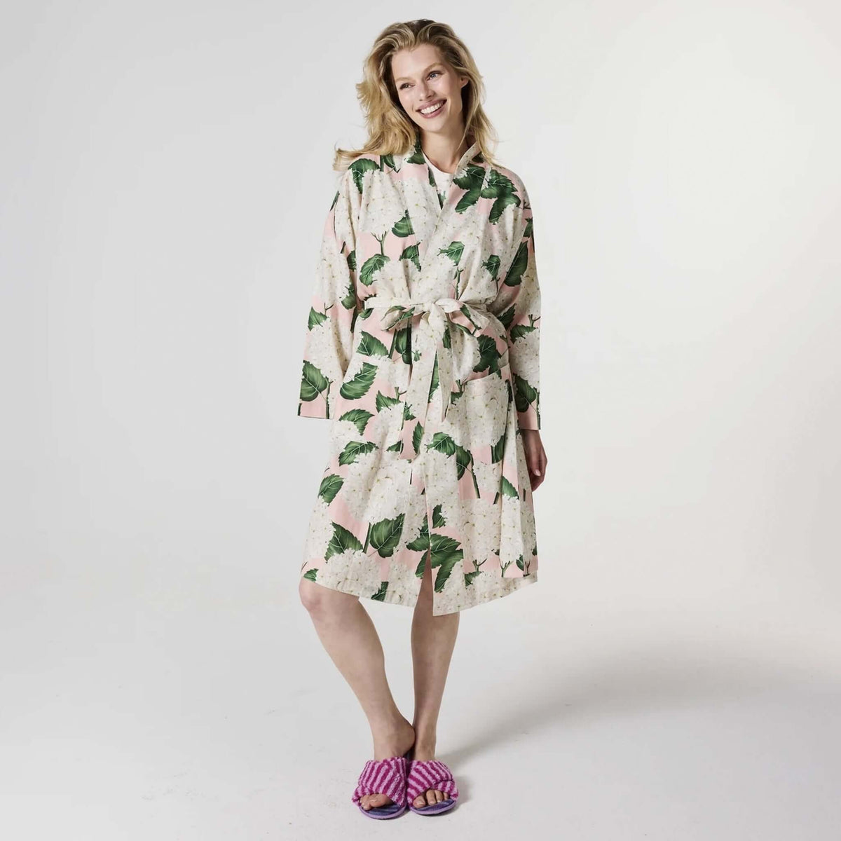Kip & Co Linen Robe - Hydrangea Pink worn by a smiling woman, showcasing floral design and casual, comfortable style.