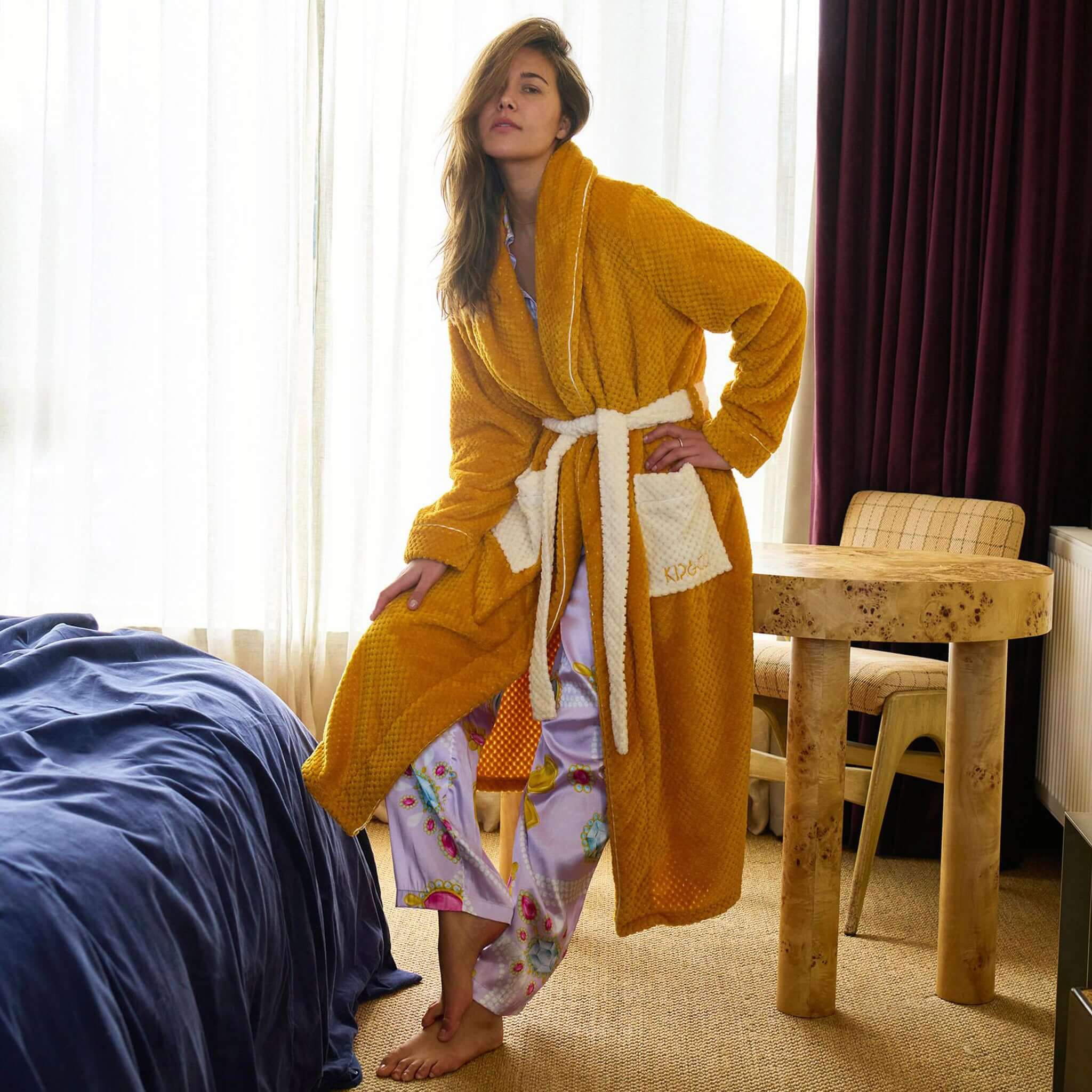 Alt Tag: Kip & Co Cosy Robe - Desert Sand quilted mustard robe with cream patch pockets and waist tie, worn indoors for cosy relaxation