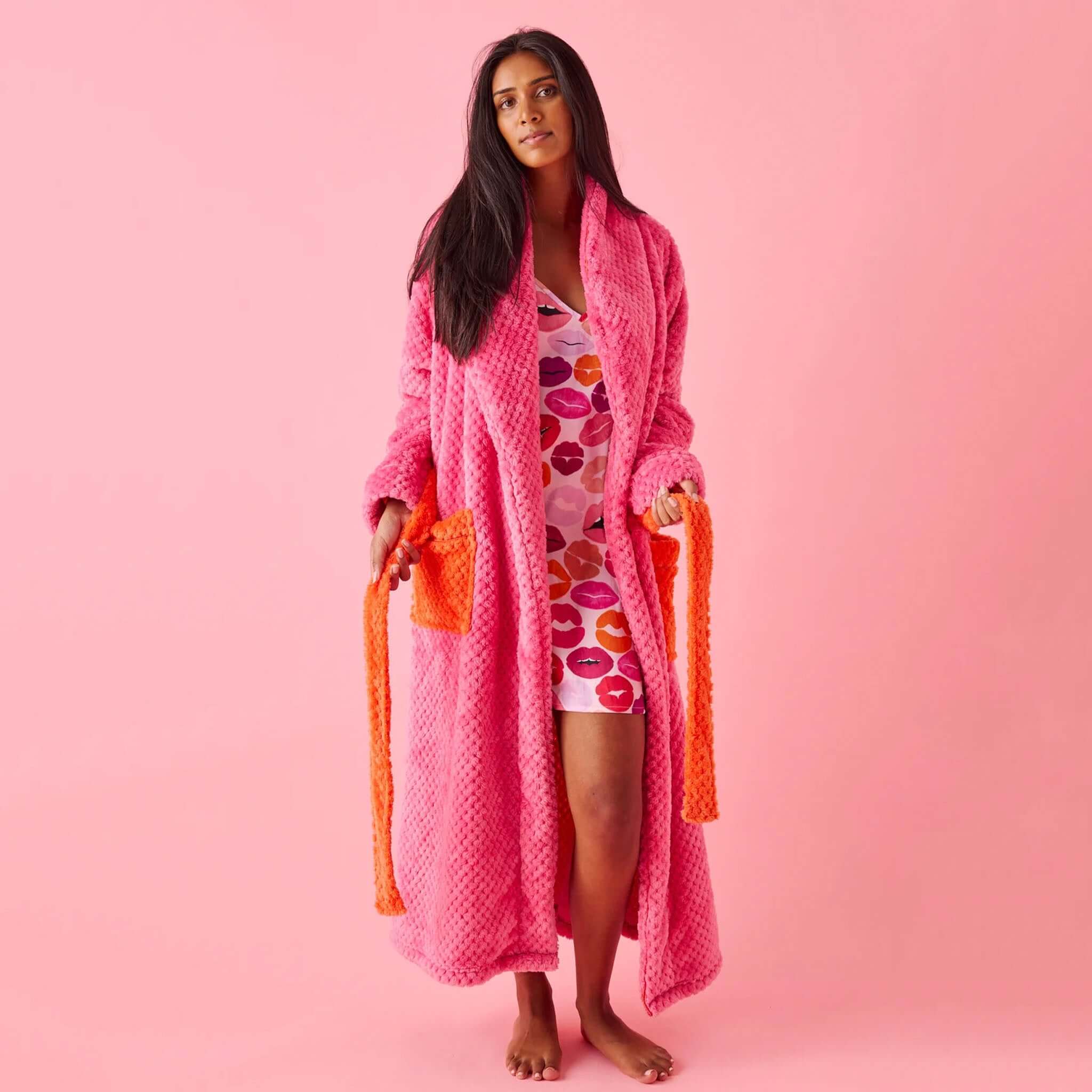 Kip & Co Cosy Robe - Kiss Me plush pink recycled polyester robe with orange tie belt, model wearing on pink background