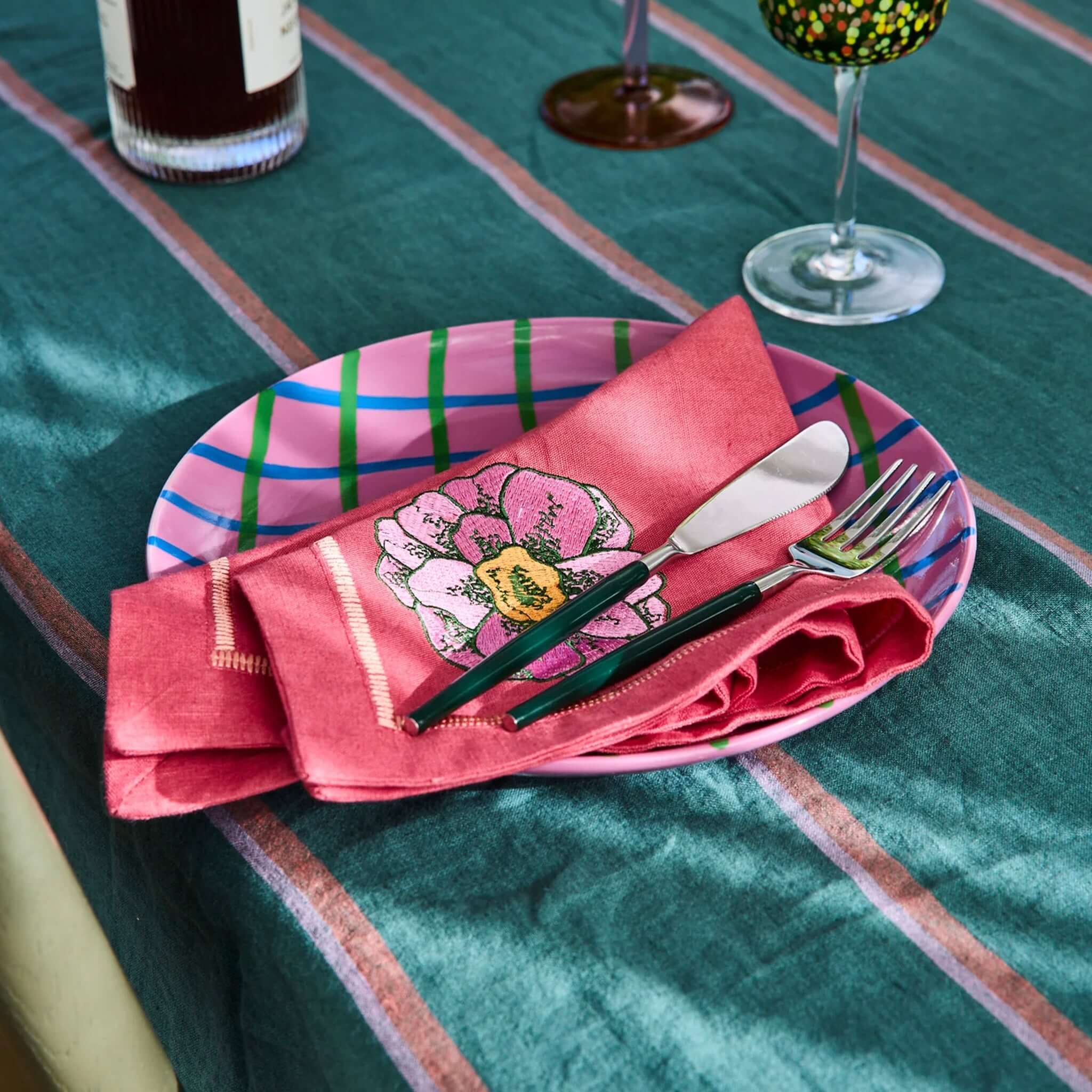 Alt Tag: Kip & Co Embroidered Linen Napkin Set - In Bloom pink embroidered linen napkin styled on striped table with cutlery