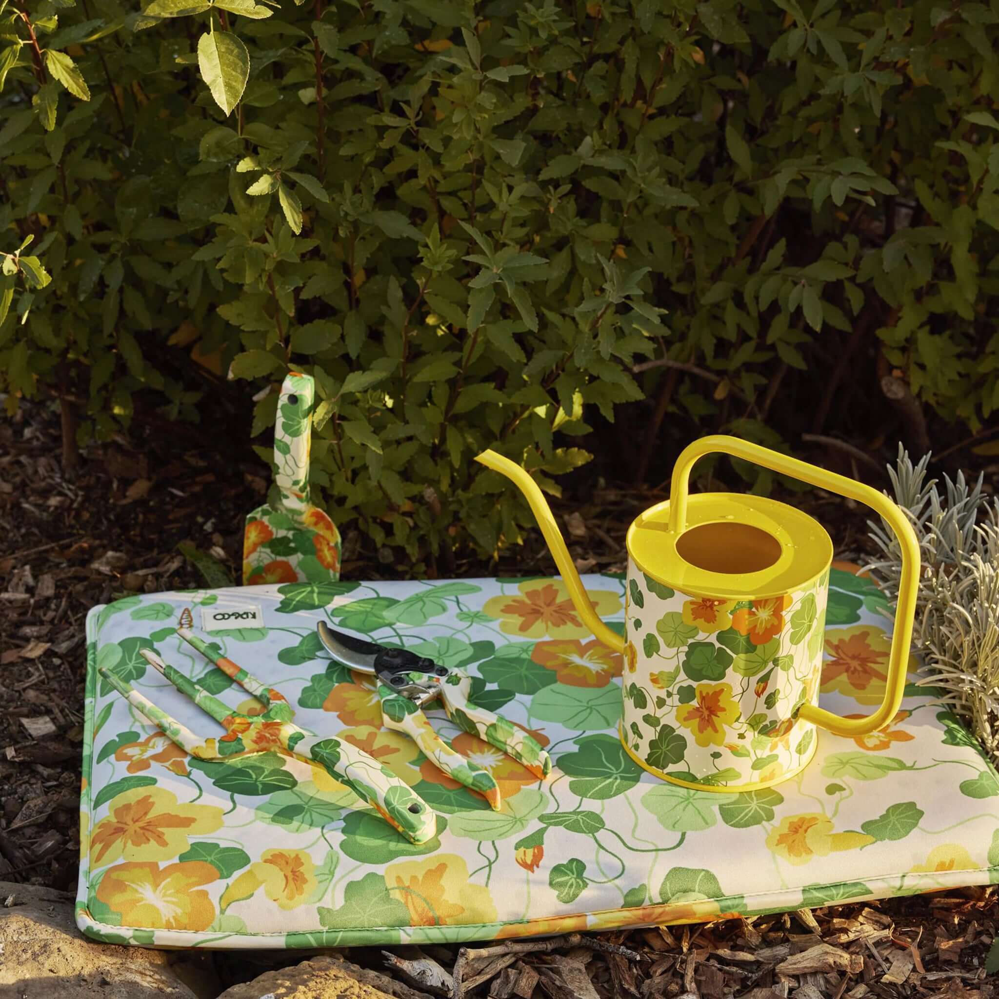 Alt Tag: Kip & Co Garden Kneeling Mat - Nasturtium with leafy print and yellow-orange flowers, outdoor gardening mat with tools and watering can