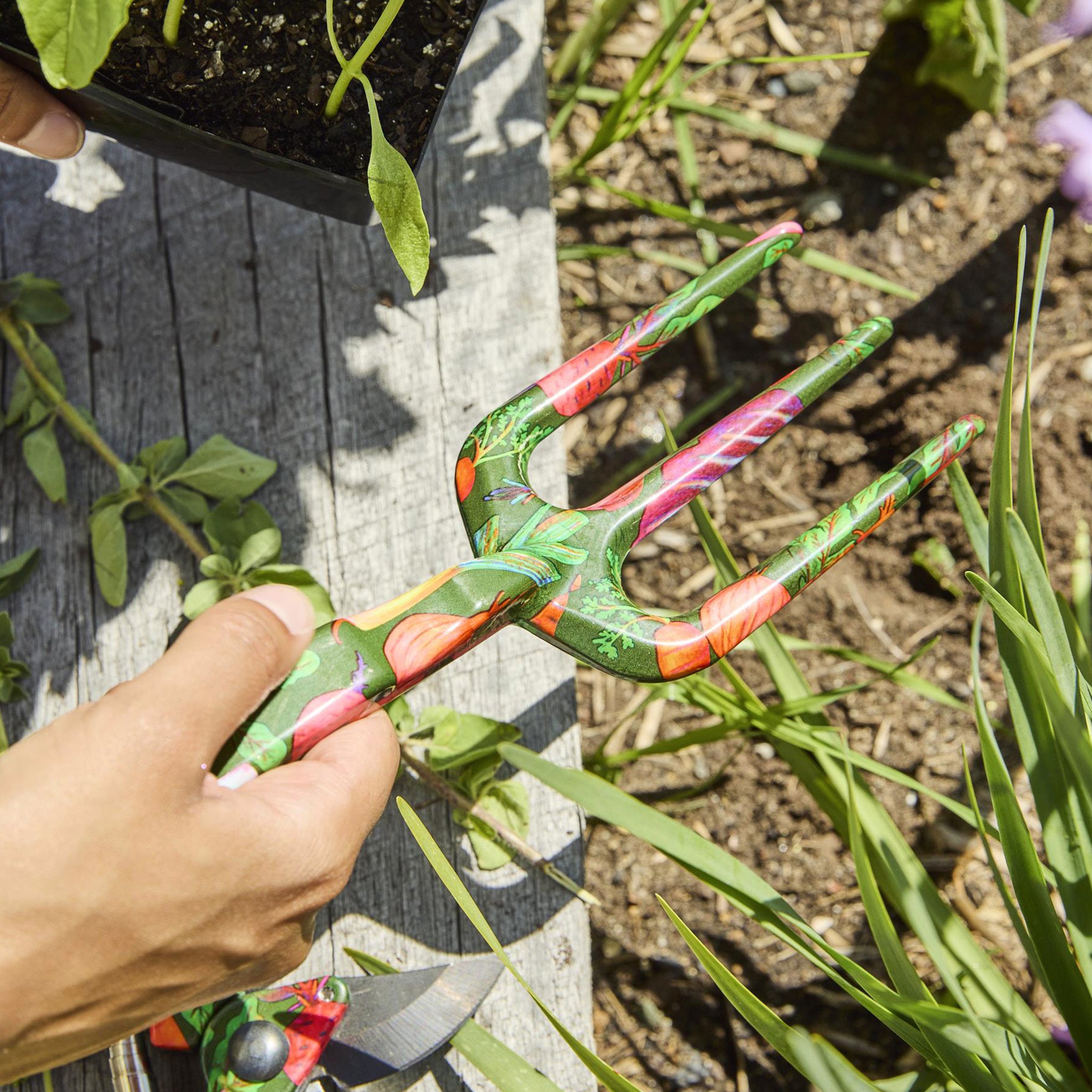 Colorful garden tool held by a hand in a garden setting