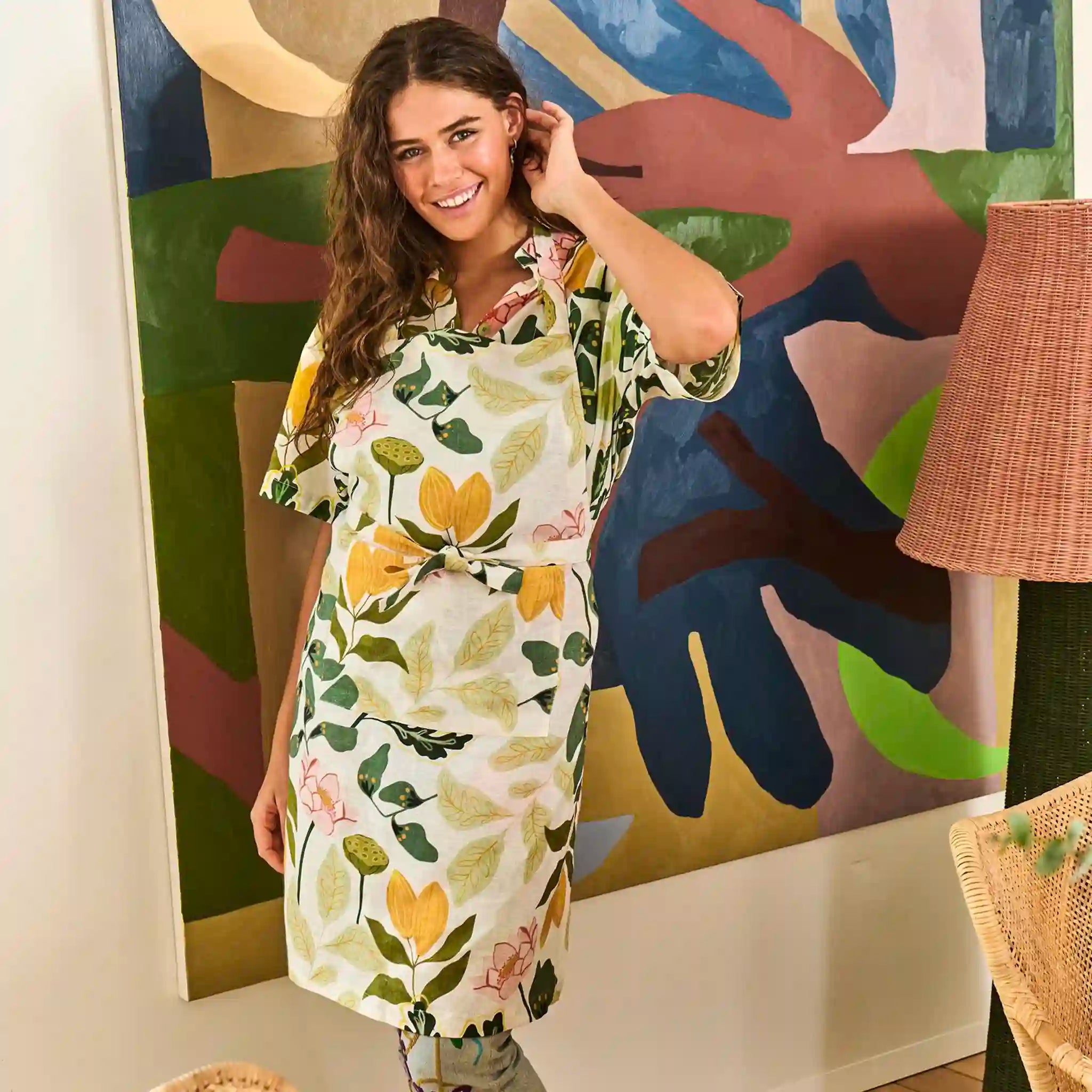Woman in a floral dress standing in front of a colorful abstract painting
