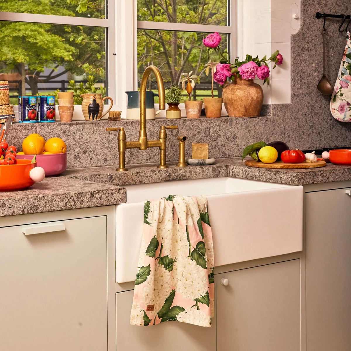 Kip & Co Linen & Cotton Tea Towel - Hydrangea Pink hanging in a colorful kitchen with a farmhouse sink.