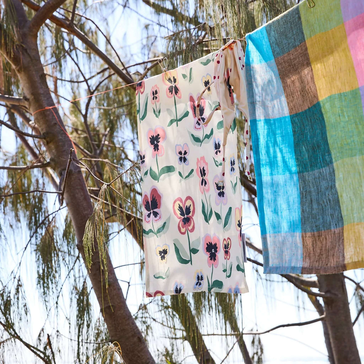 Kip & Co Linen & Cotton Tea Towel - Pretty Pansy hanging on a clothesline among greenery.