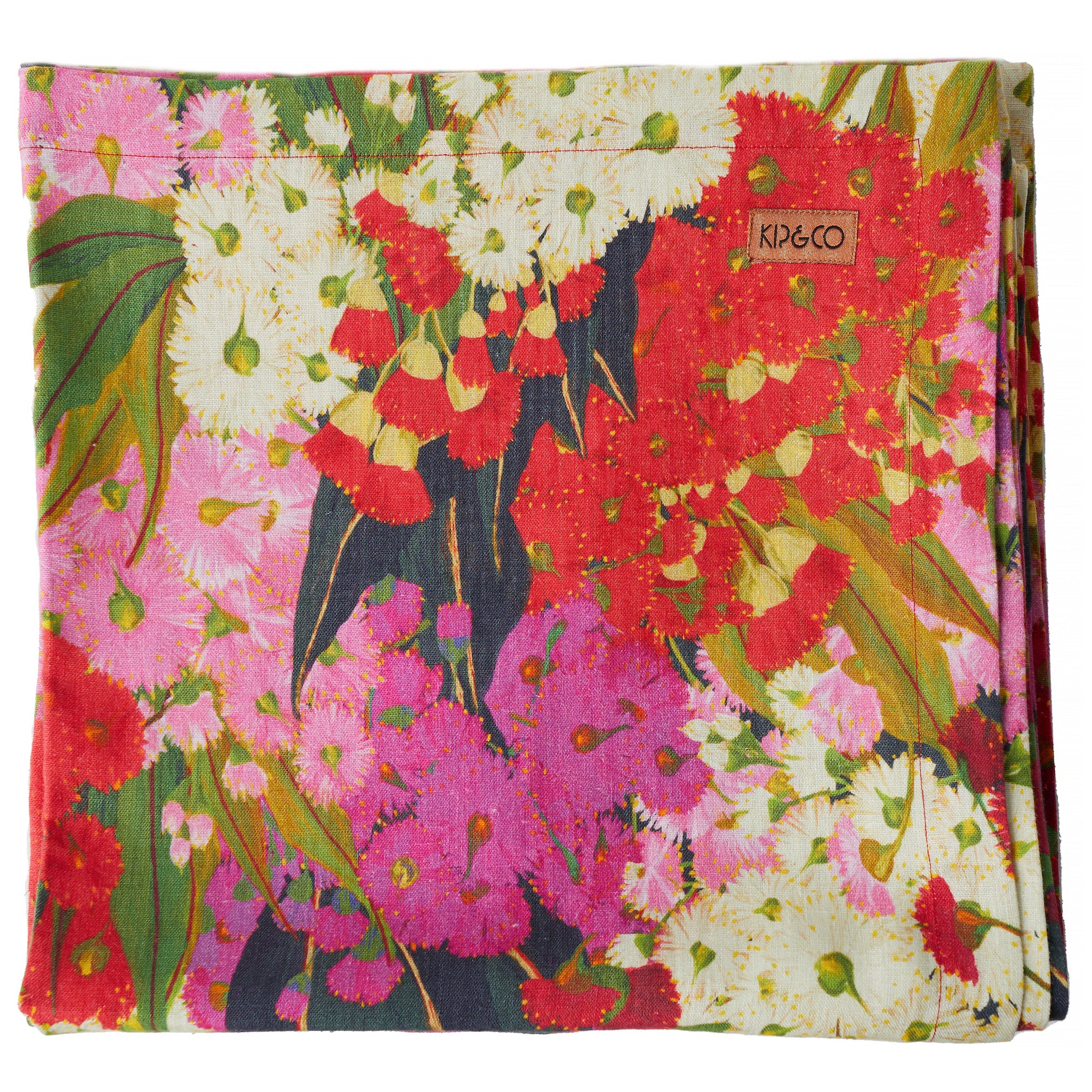A folded linen tablecloth with a floral pattern featuring rich pinks, reds, and creamy white colors.