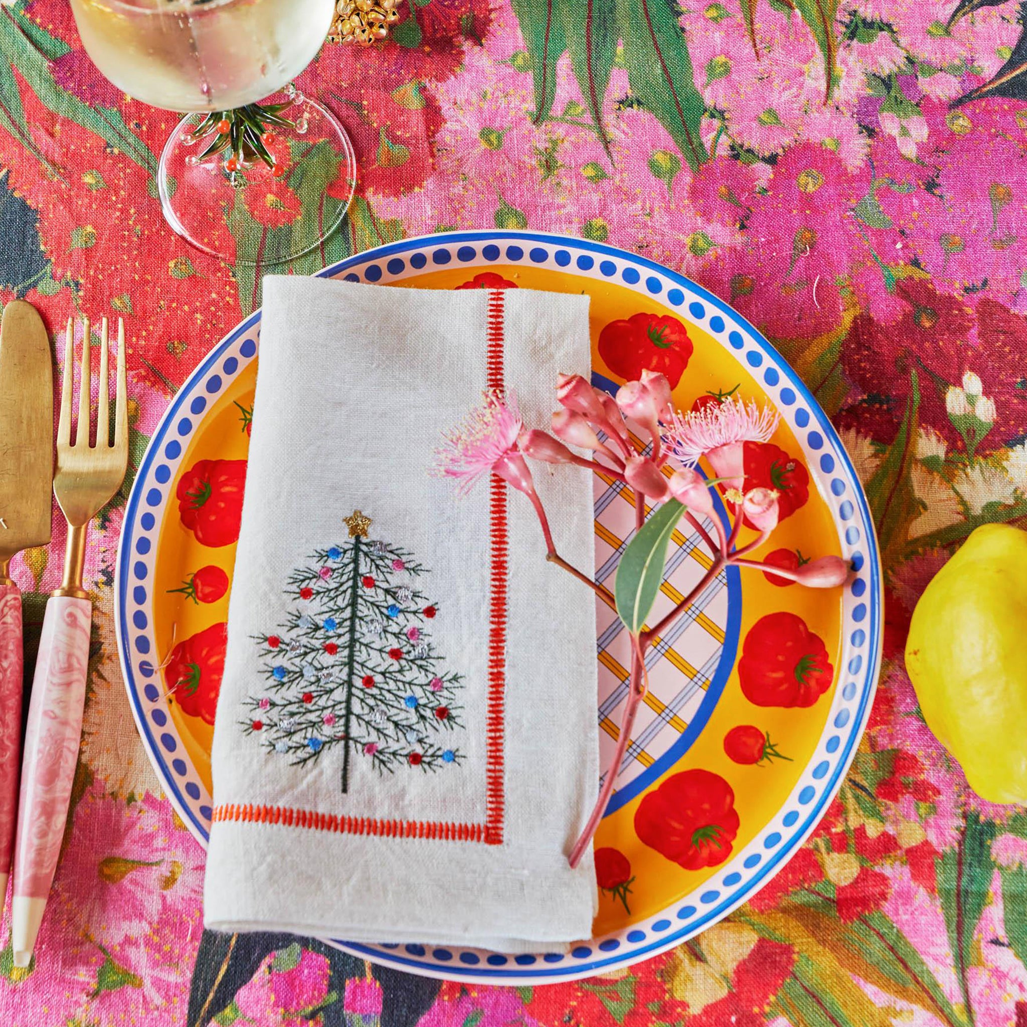 A linen tablecloth with a floral pattern featuring rich pinks, reds, and creamy white colors.