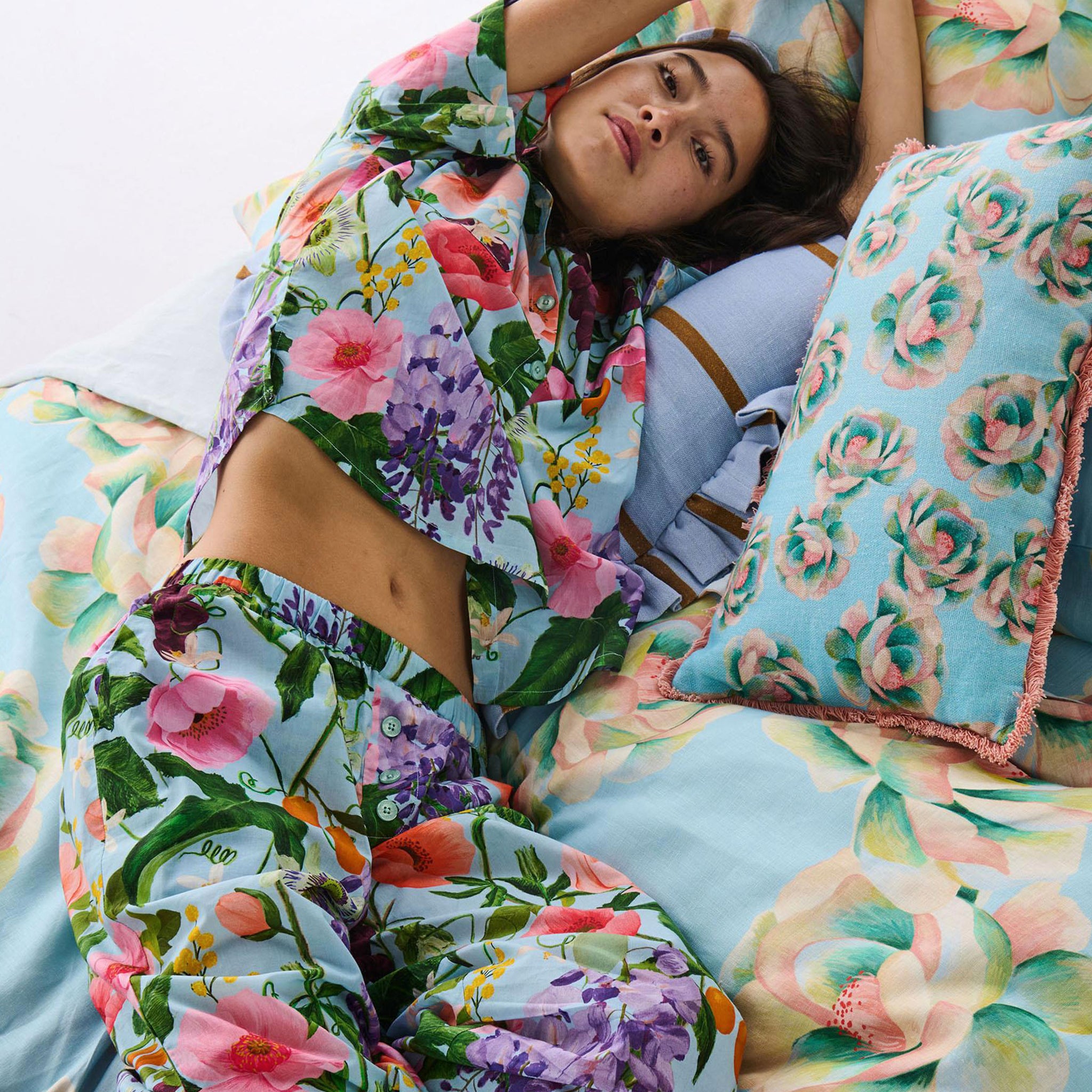 Woman lying on a bed with floral bedding and pillows