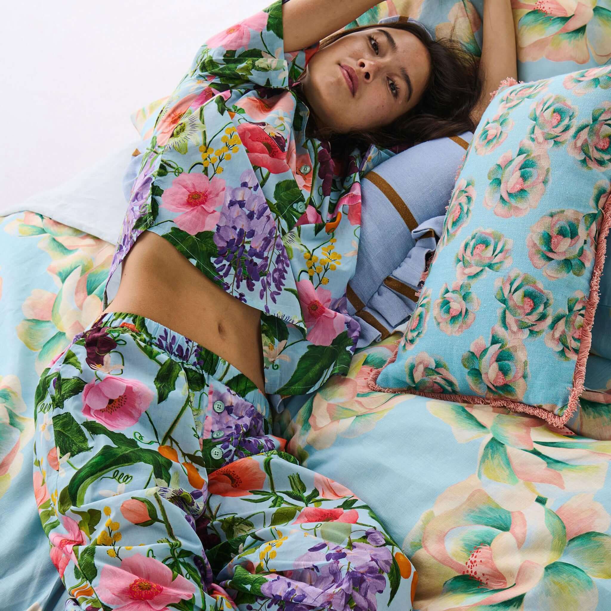 Woman lying on a bed with floral bedding and pillows