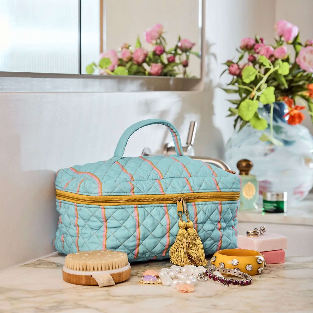 Kip & Co Quilted Toiletry Case - Aegean Stripe displayed alongside accessories on a bathroom countertop.