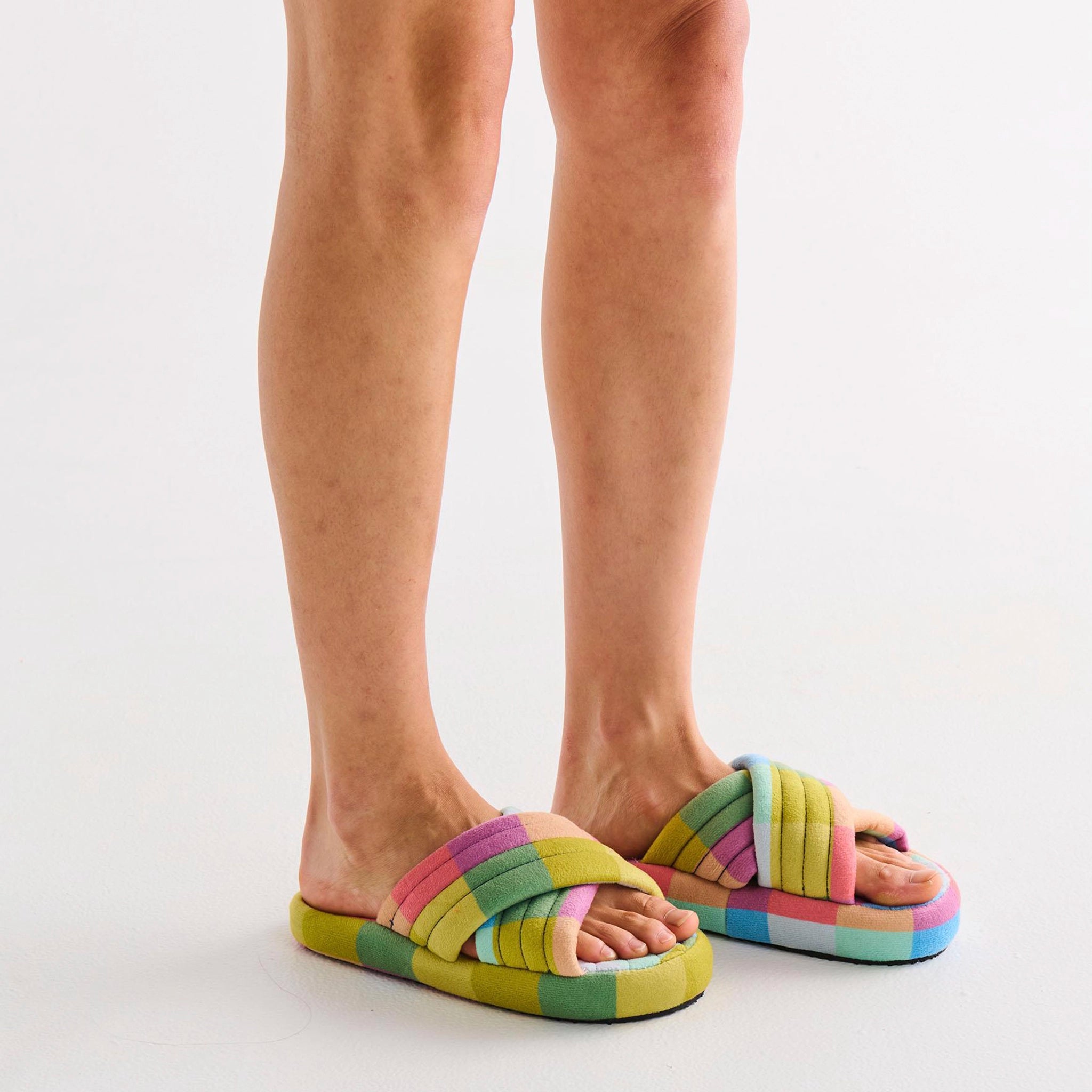 Colorful striped slippers worn by a person on a white background