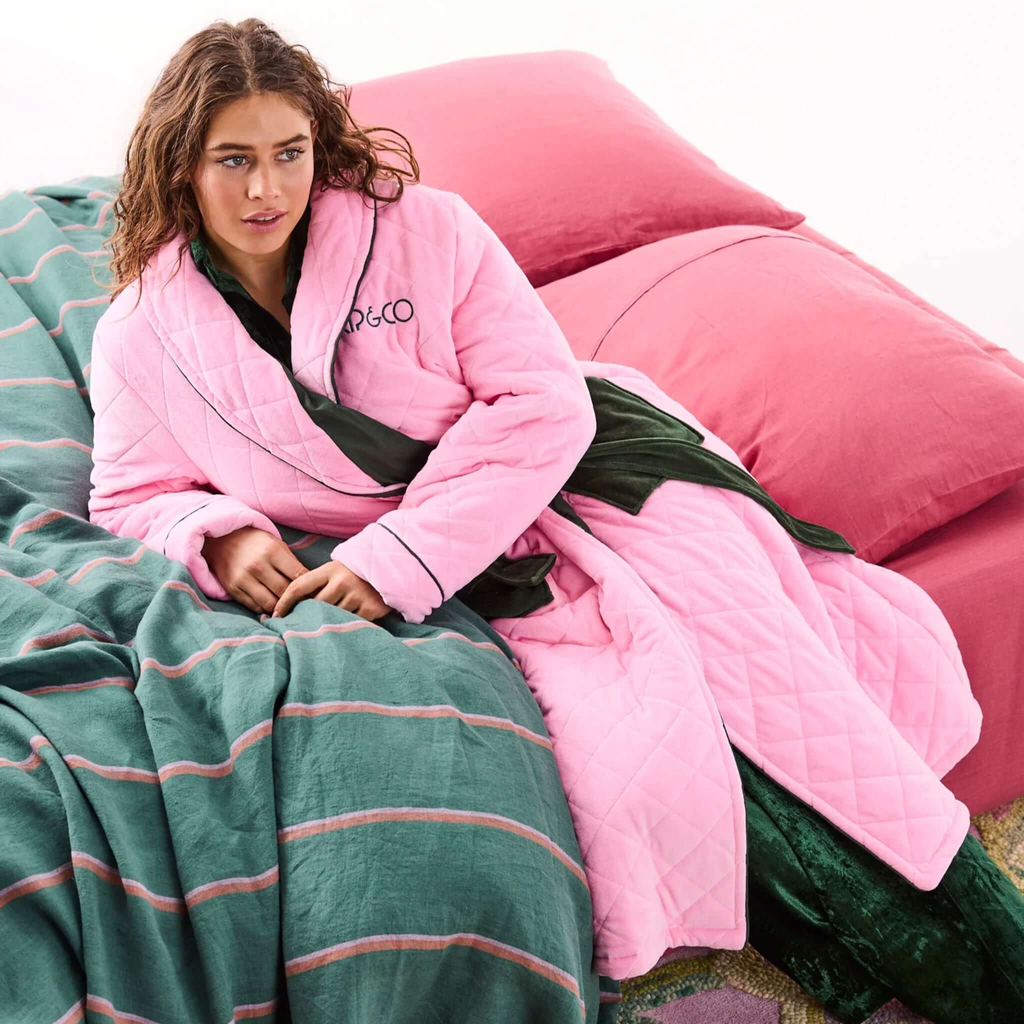 Alt Tag: Kip & Co Quilted Velvet Robe - Candy Pine pink quilted velvet robe with waist tie, styled on bed for cozy relaxation