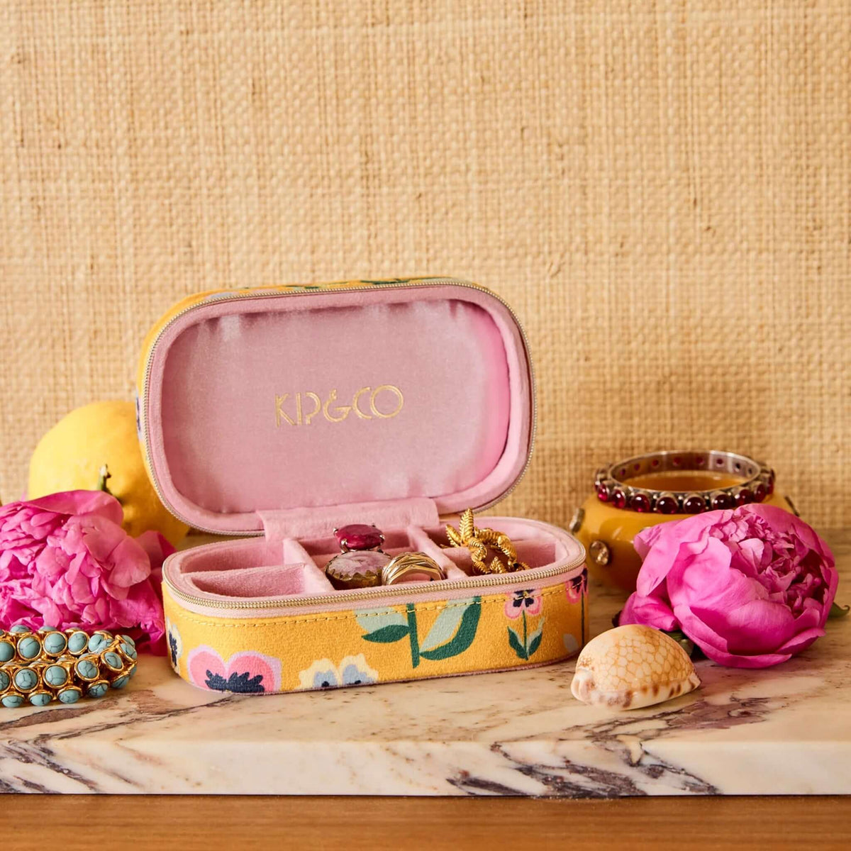 Kip & Co Travel Velvet Jewellery Box - Pretty Pansy open with compartments for rings and earrings, surrounded by flowers and accessories.
