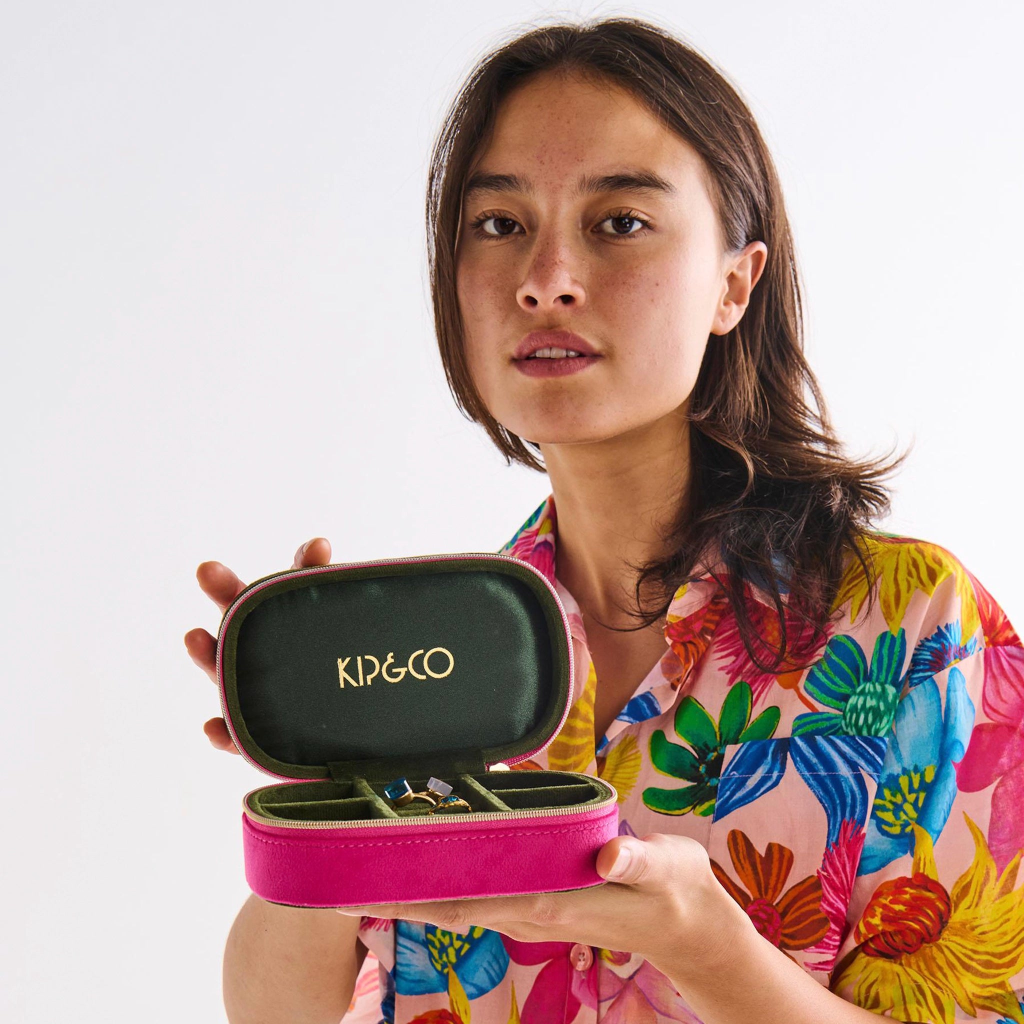 Woman holding a pink jewelry case with 'Kip & Co' branding against a white background