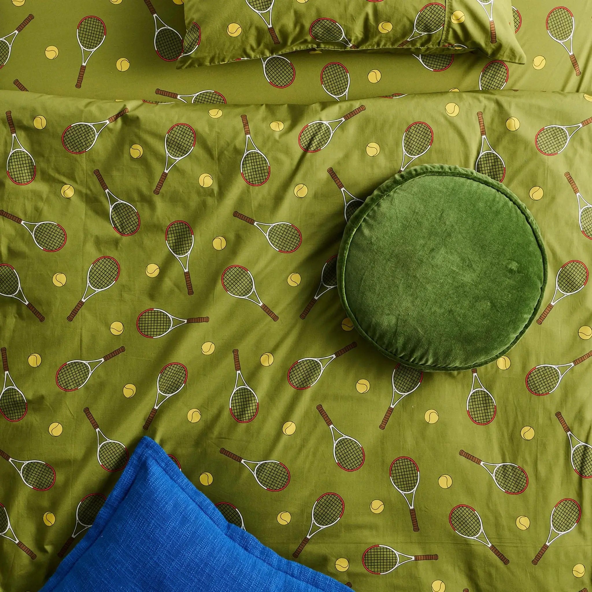 Alt Tag: Kip & Co Velvet Pea Cushion - Campsite fern green round cotton velvet cushion on tennis print bedding