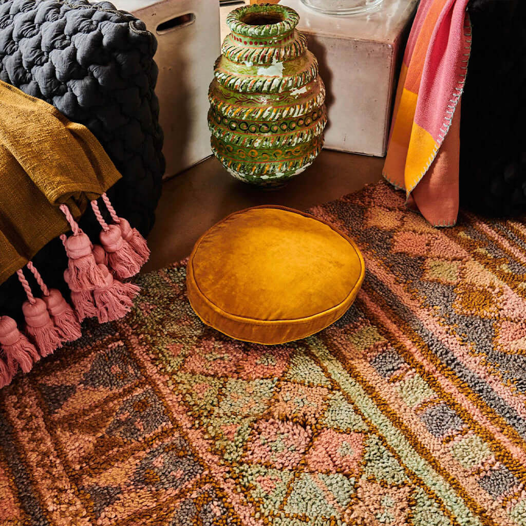Alt Tag: Kip & Co Velvet Pea Cushion - Pecan light brown round velvet cushion on patterned rug in styled home interior