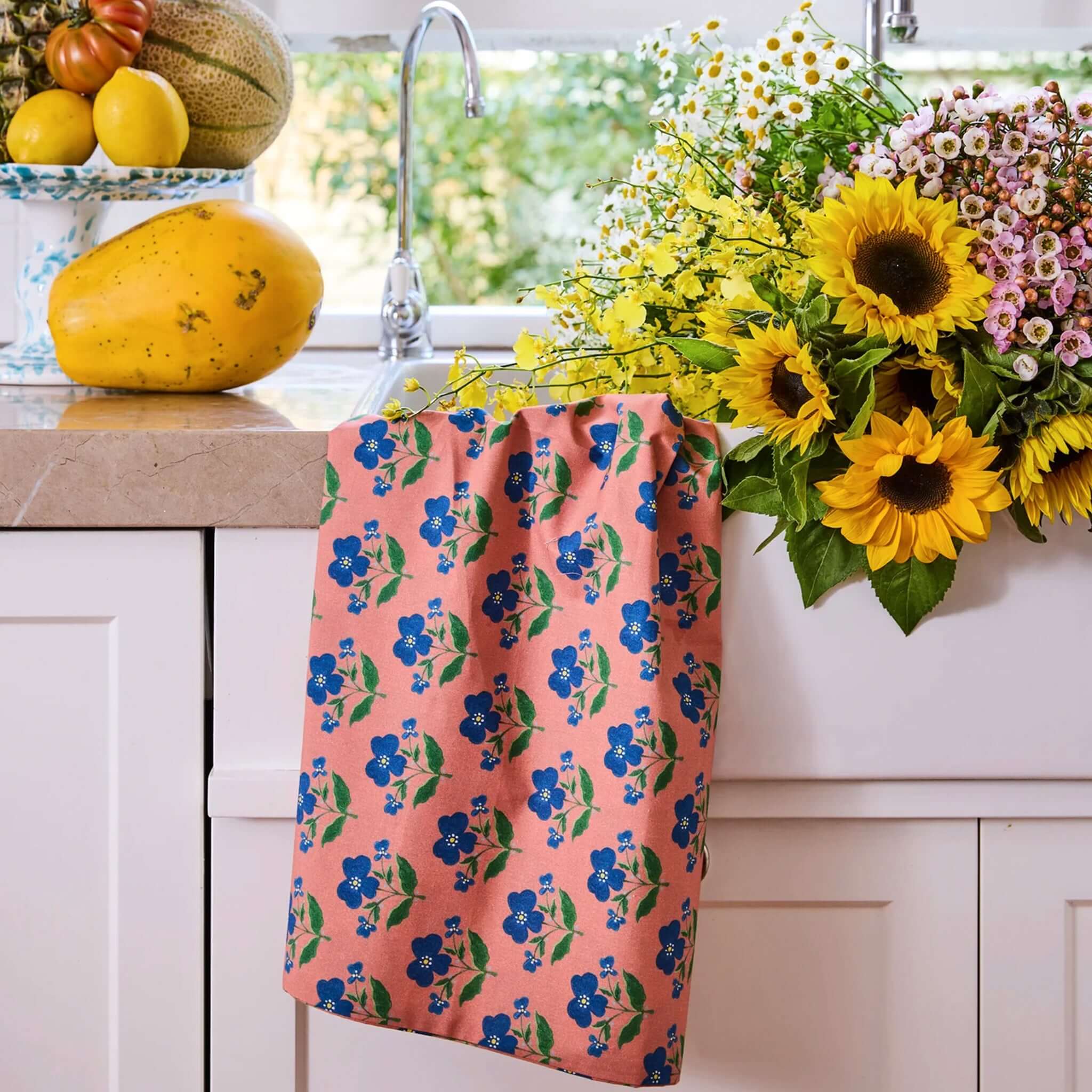 Kip & Co x Anna Spiro Linen & Cotton Tea Towel - Indian Summer Rose hanging by the sink with flowers and fruits.