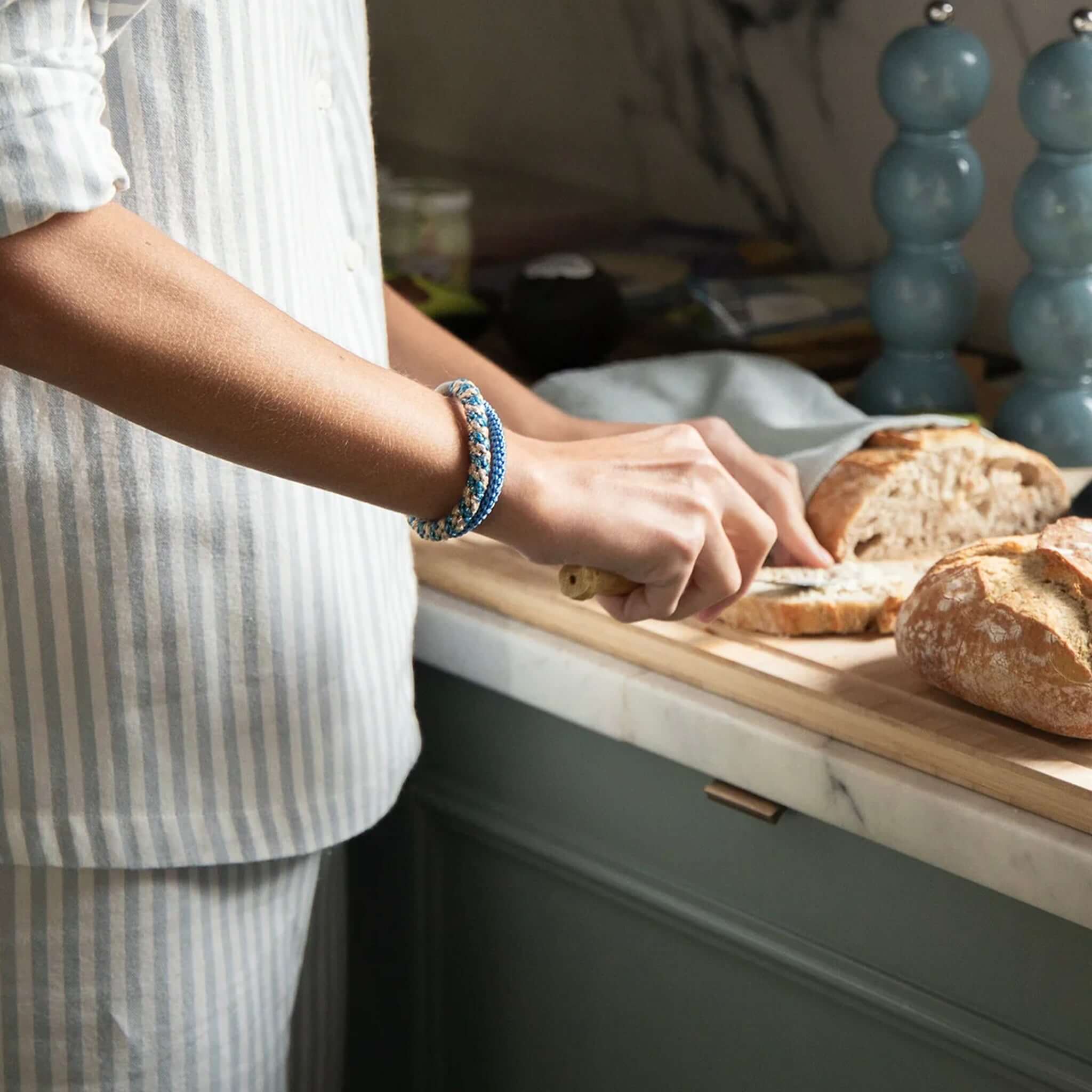 Kknekki Hair Tie - Purple Blue Glitter worn by a person slicing bread in a kitchen setting.