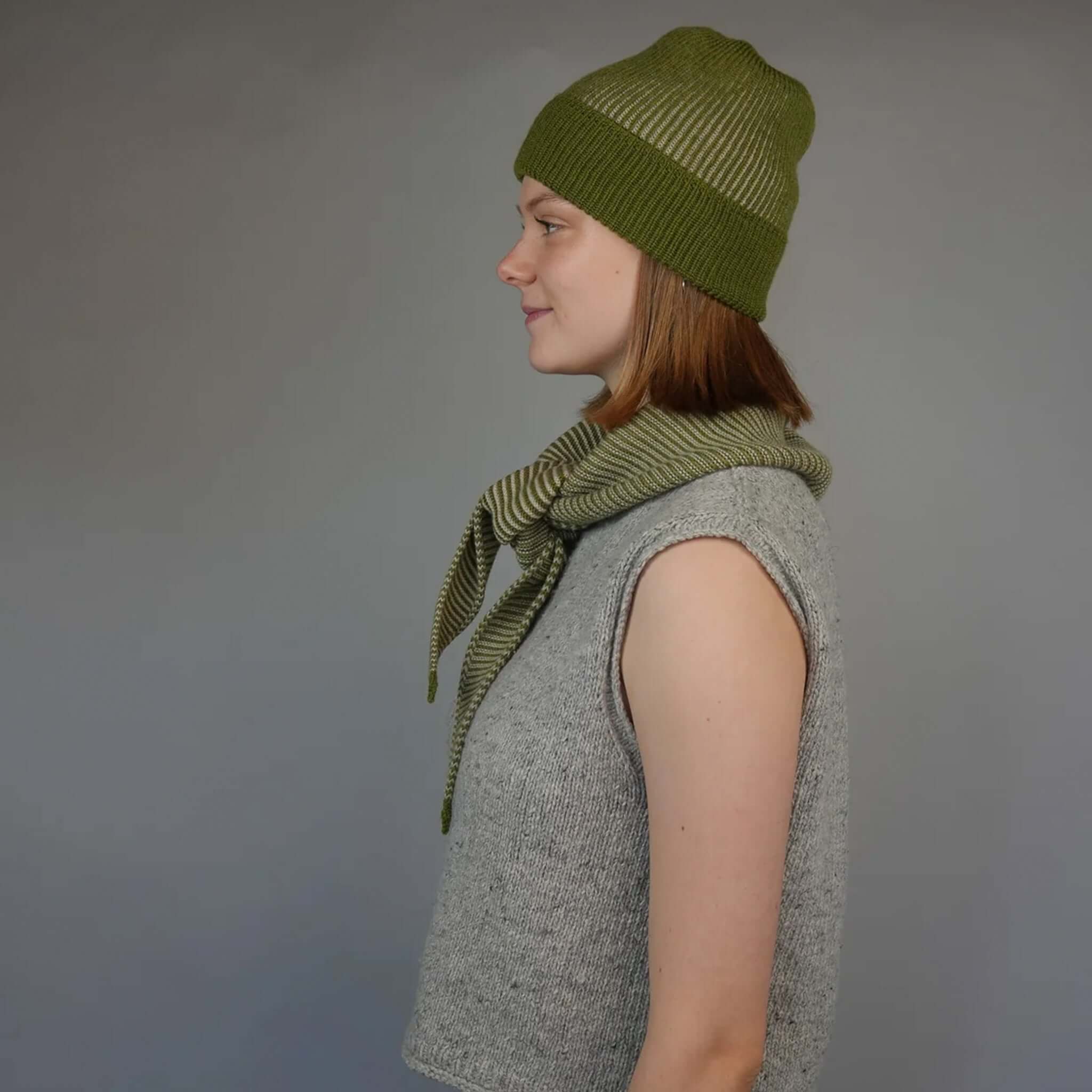 Knit Shepherd Punakaiki Merino Neckerchief - Pikopiko Green styled with matching hat, model wearing garter stitch textile.
